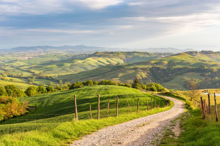 Rural view of the valley with a rolling landscape and a dirt road in tuscany, italy