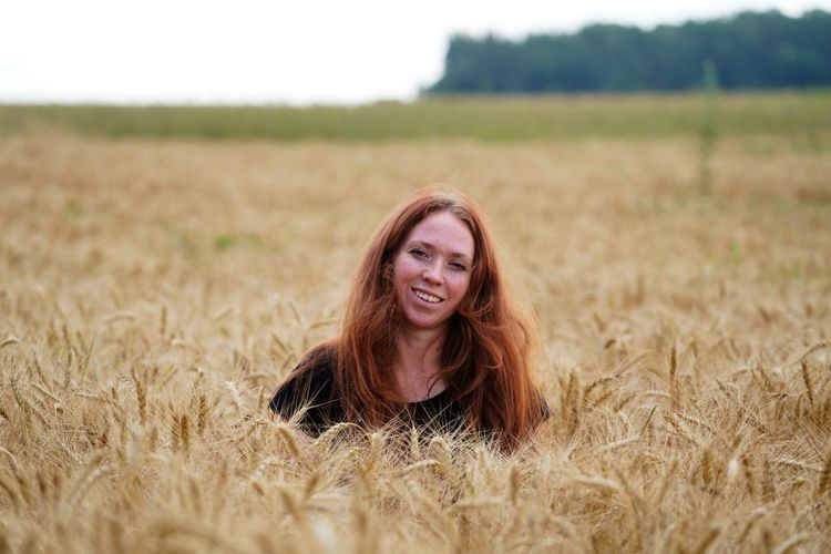 Portrait of smiling beautiful red hair young woman in wheat field
