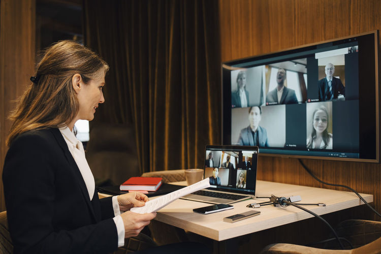 Businesswoman discussing with male and female colleagues on video call through laptop in office