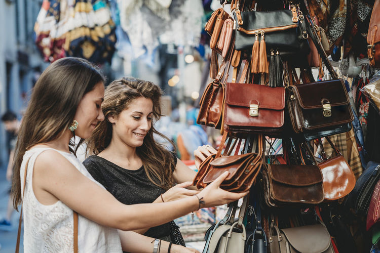 Female friends buying purse at market