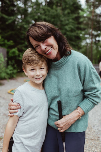 Portrait of smiling grandmother with grandson standing outdoors