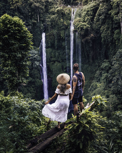 Rear view of couple enjoying waterfall in forest