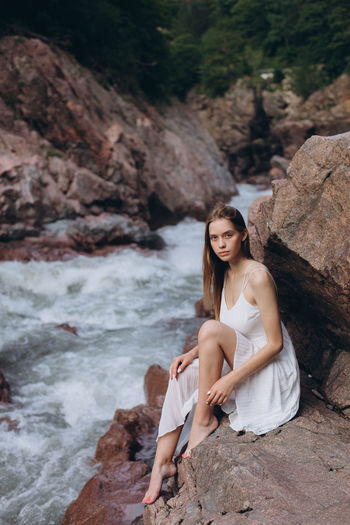 Portrait of beautiful young woman sitting by river