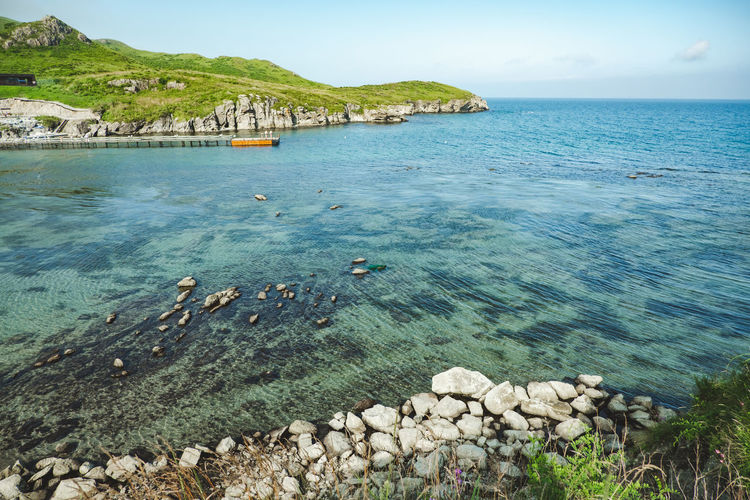 Summer sea panorama.  shallow transparent sea with reefs, rocks and green hills around. japan sea.
