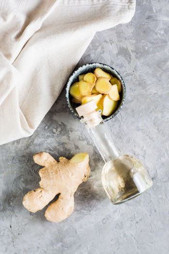 Bottle with natural ginger serum and chopped ginger in a bowl on the table. natural care cosmetics. 