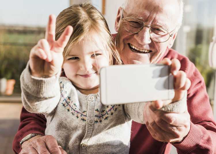 Grandfather and granddaughter taking selfies with a smart phone