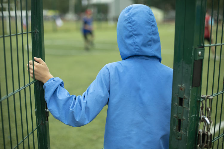 Door to stadium. child holds grille. boy walks into schoolyard. football viewer.