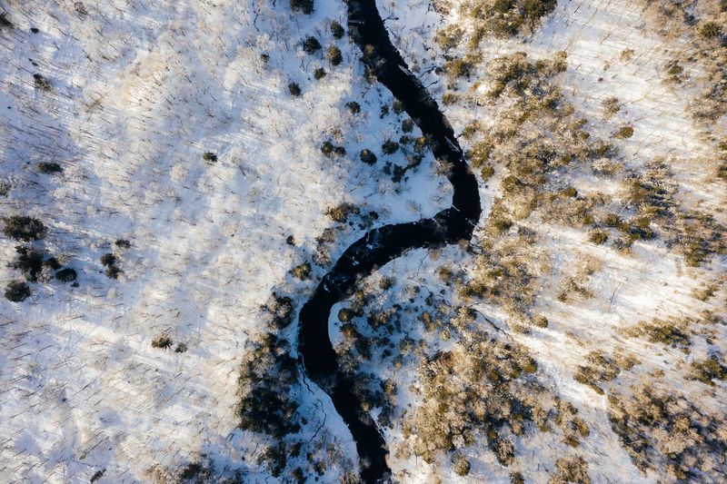Aerial view of river amidst snow covered field
