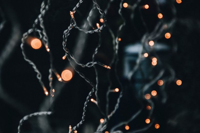 Close-up of fairy lights hanging against black background