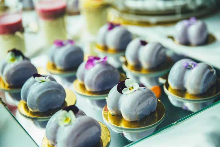 Purple mousse cakes on a mirrored tray, decorated with a violet flower