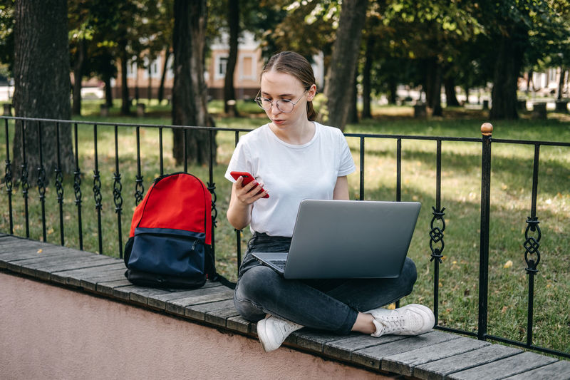 Young woman using laptop while sitting on sofa at park