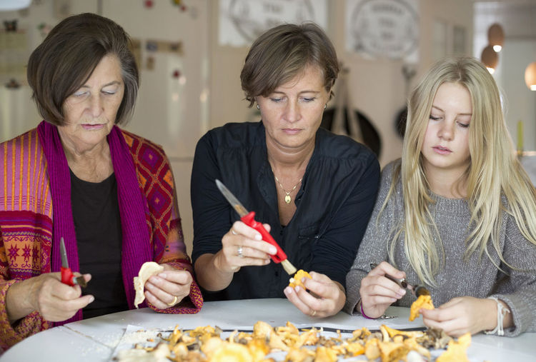 Three generation females cleaning chanterelle mushroom at home