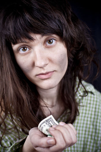 Close-up portrait of young woman holding banknote