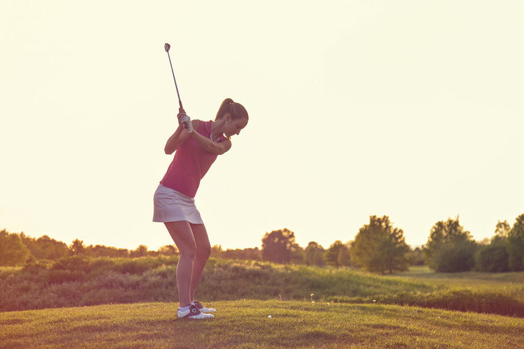 Woman playing golf against sky