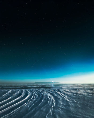 A man in scenic view of snowy landscape against sky at night