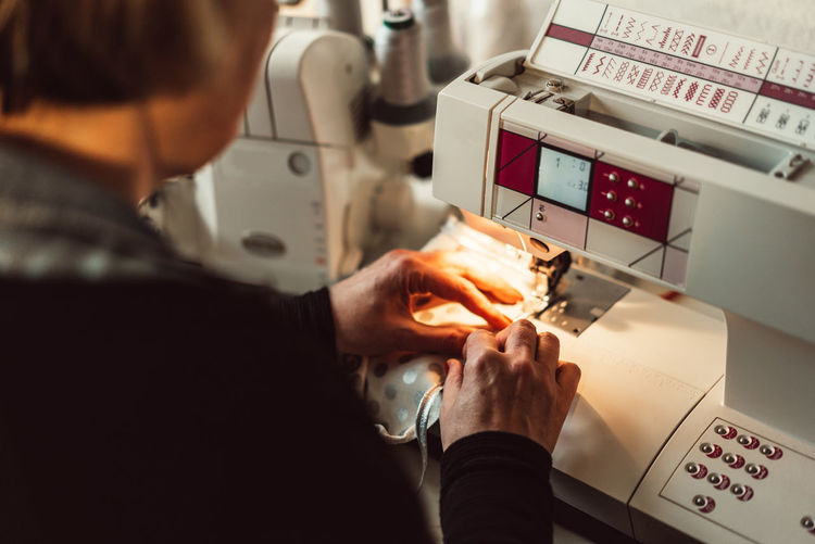 Cropped image of woman stitching fabric on sewing machine