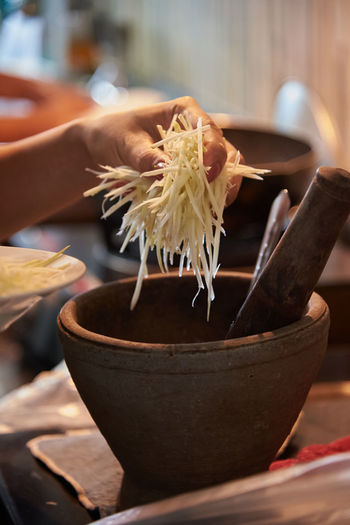Chef putting the sliced green papaya to the mortar