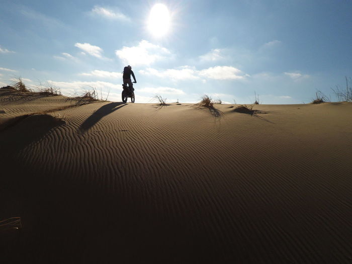 Man walking on sand at desert against sky