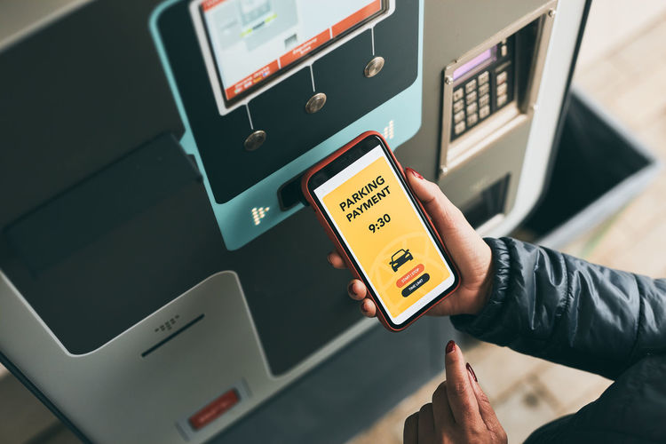 Paying for parking ticket at car parking payment machine using mobile app on smartphone. parking fee