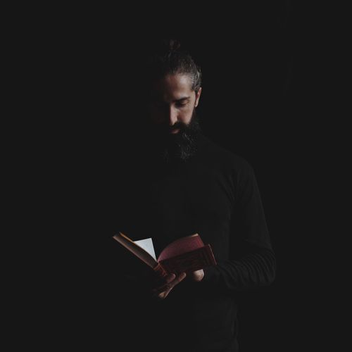 Priest reading bible against black background