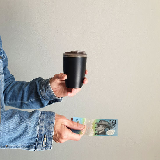 Person paying for coffee with australian money holding reusable coffee cup