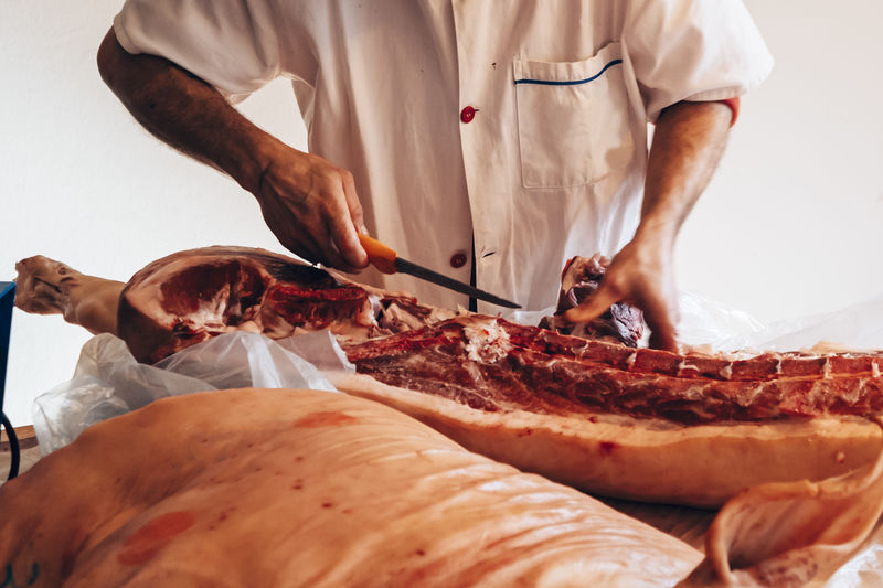 Close up of a butcher cutting a pig carcass
