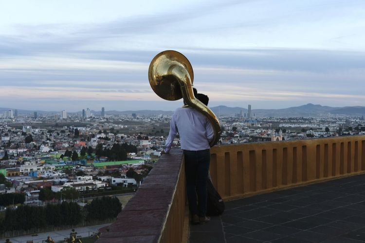 Rear view of man standing in city against sky