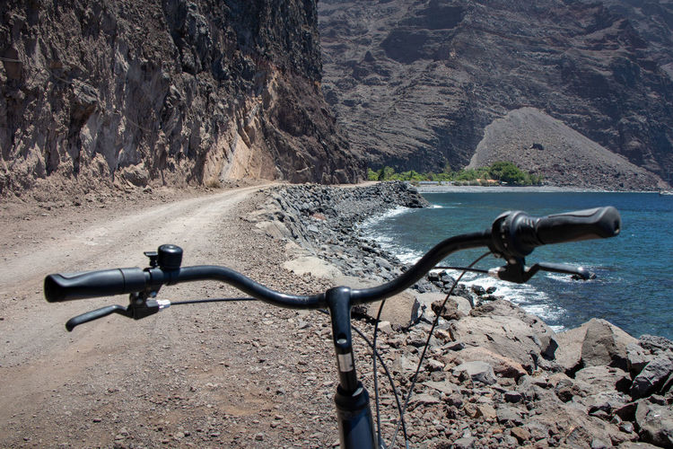 Bicycle on rock by sea against mountains