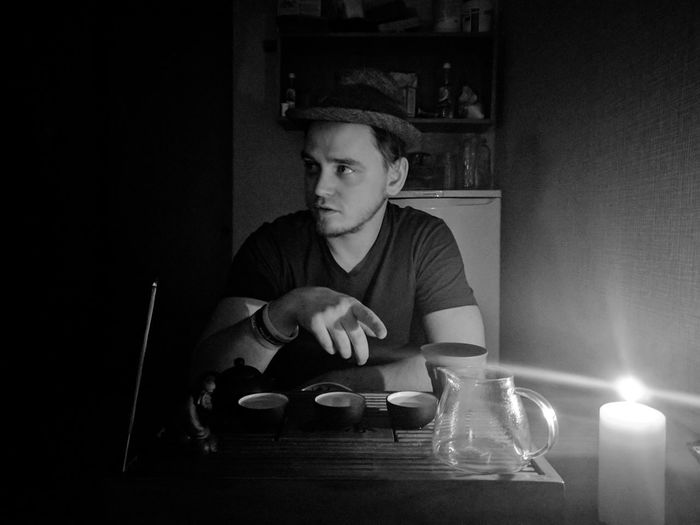 Young man sitting on illuminated dinning table at home