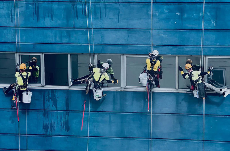Team of workers painting wall high rise building. painters are painting exterior office buildings. 