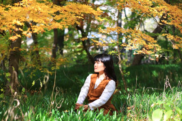 Beautiful woman looking away while sitting in grass at park