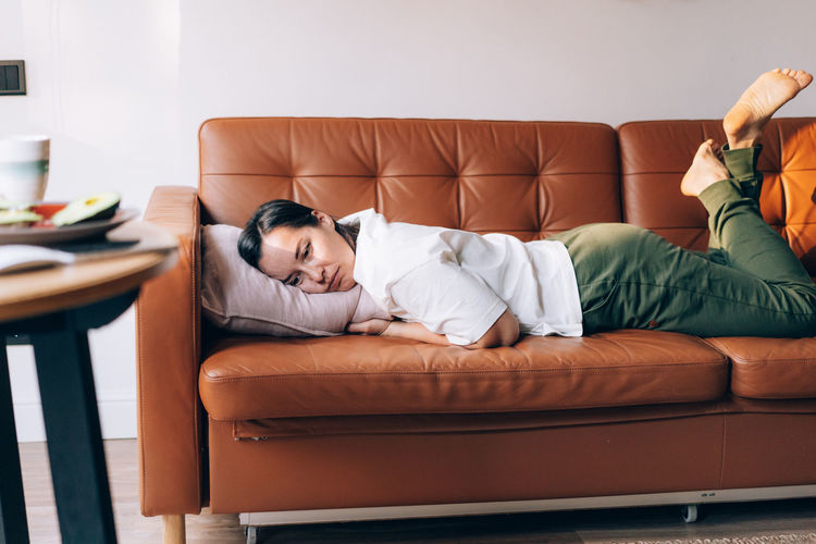Low section of woman sitting on sofa at home