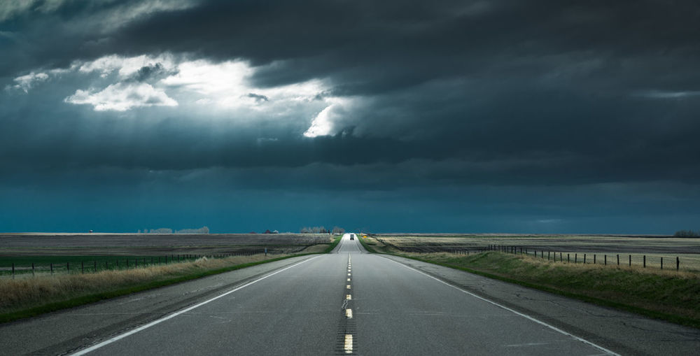 Diminishing perspective of road against cloudy sky