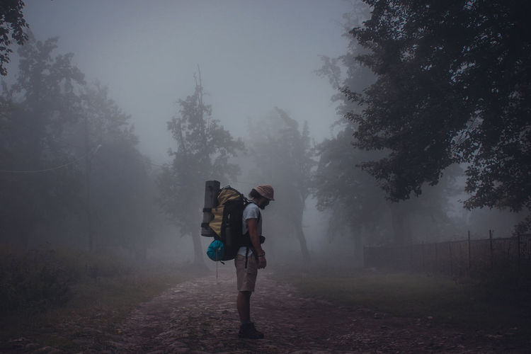 Side view of backpacker standing in forest