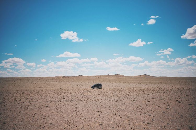Off-road vehicle at gobi desert against sky