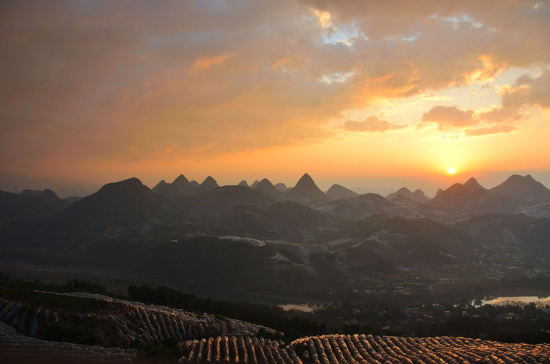 Scenic view of mountains against dramatic sky during sunset