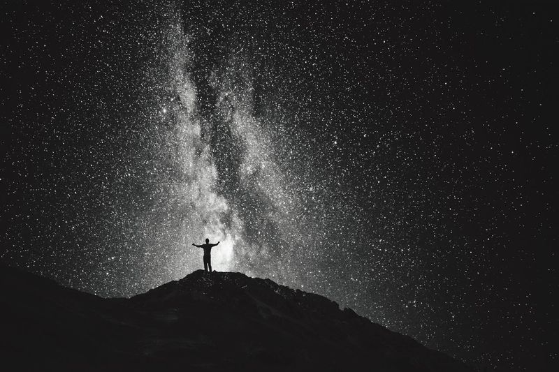 Low angle view of silhouette man against star field at night