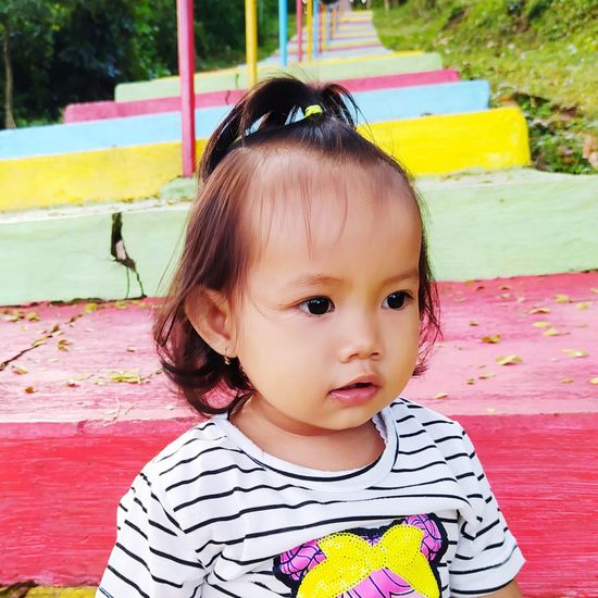 Close-up of cute baby girl looking away against colorful steps