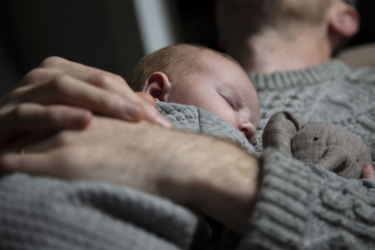 Midsection of father embracing baby while lying at home