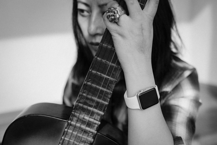 Woman looking away while holding guitar