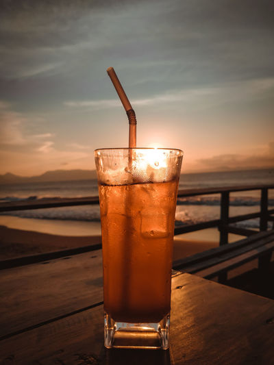Close-up of drink on table against sunset