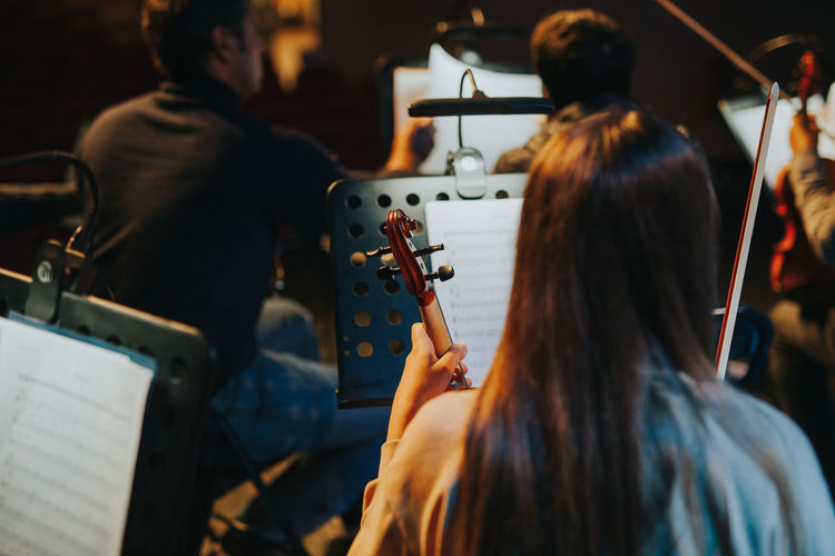 Rear view of woman playing violin during orchestra