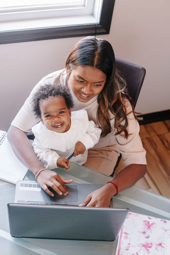 Mixed race indian mother with african black baby working online from home. workplace of freelancer 