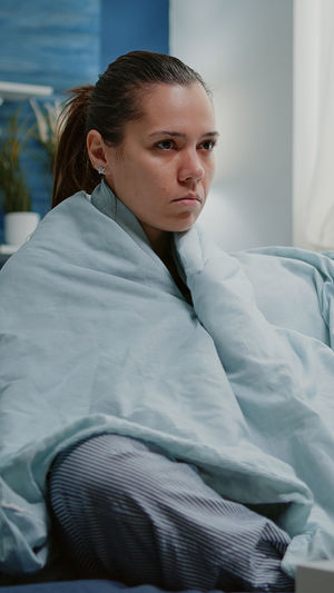 Portrait of young woman sitting on bed at home
