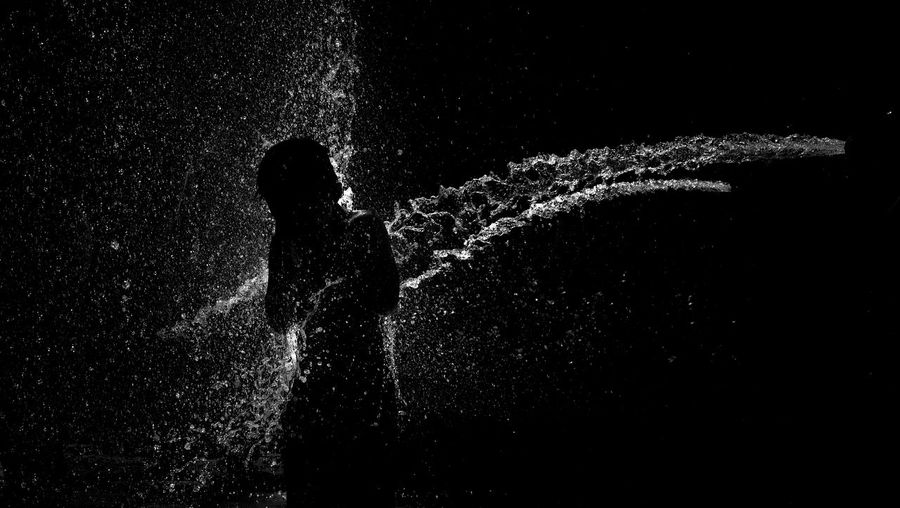 Silhouette of man standing in water at night
