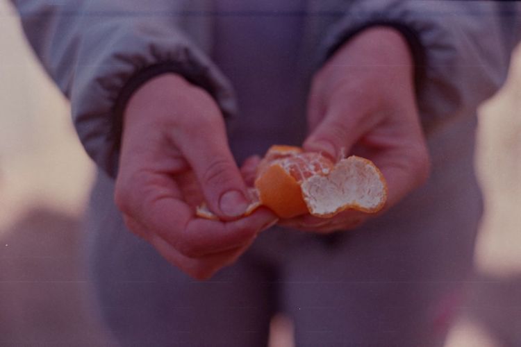 Low section of woman peeling mandarin
