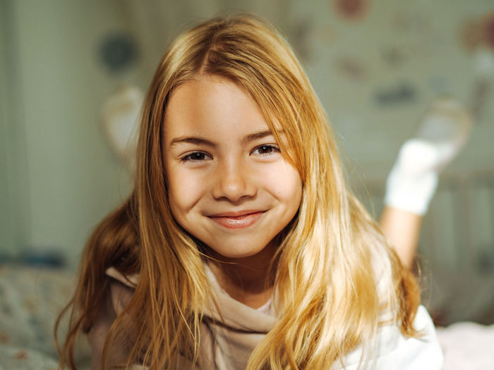 Beautiful caucasian tennage girl having fun and smiling on a bed in bedroom