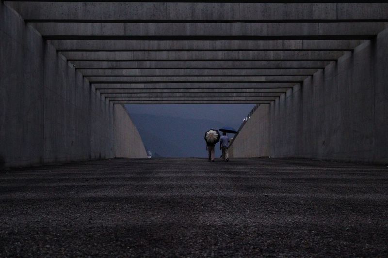 Rear view of people walking in tunnel