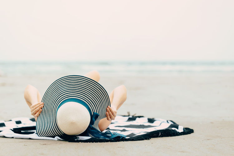 Man relaxing on sand at beach against clear sky