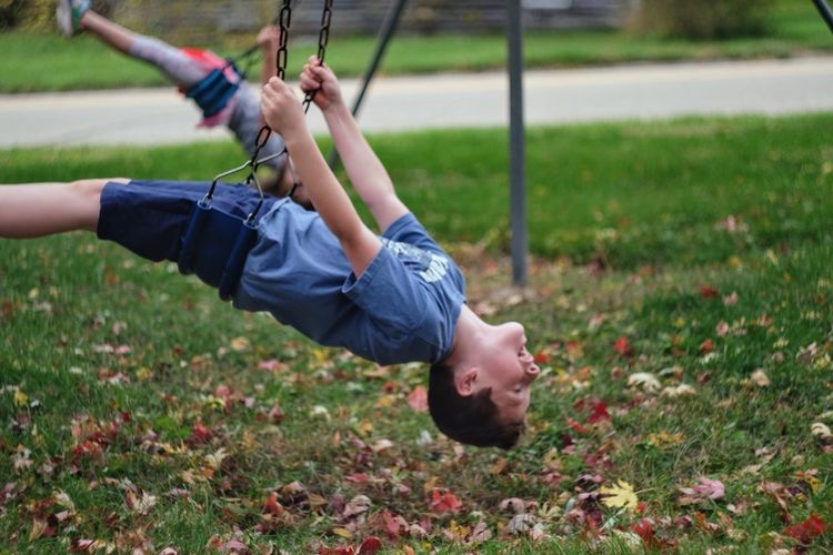 Side view of boy enjoying on swing at park
